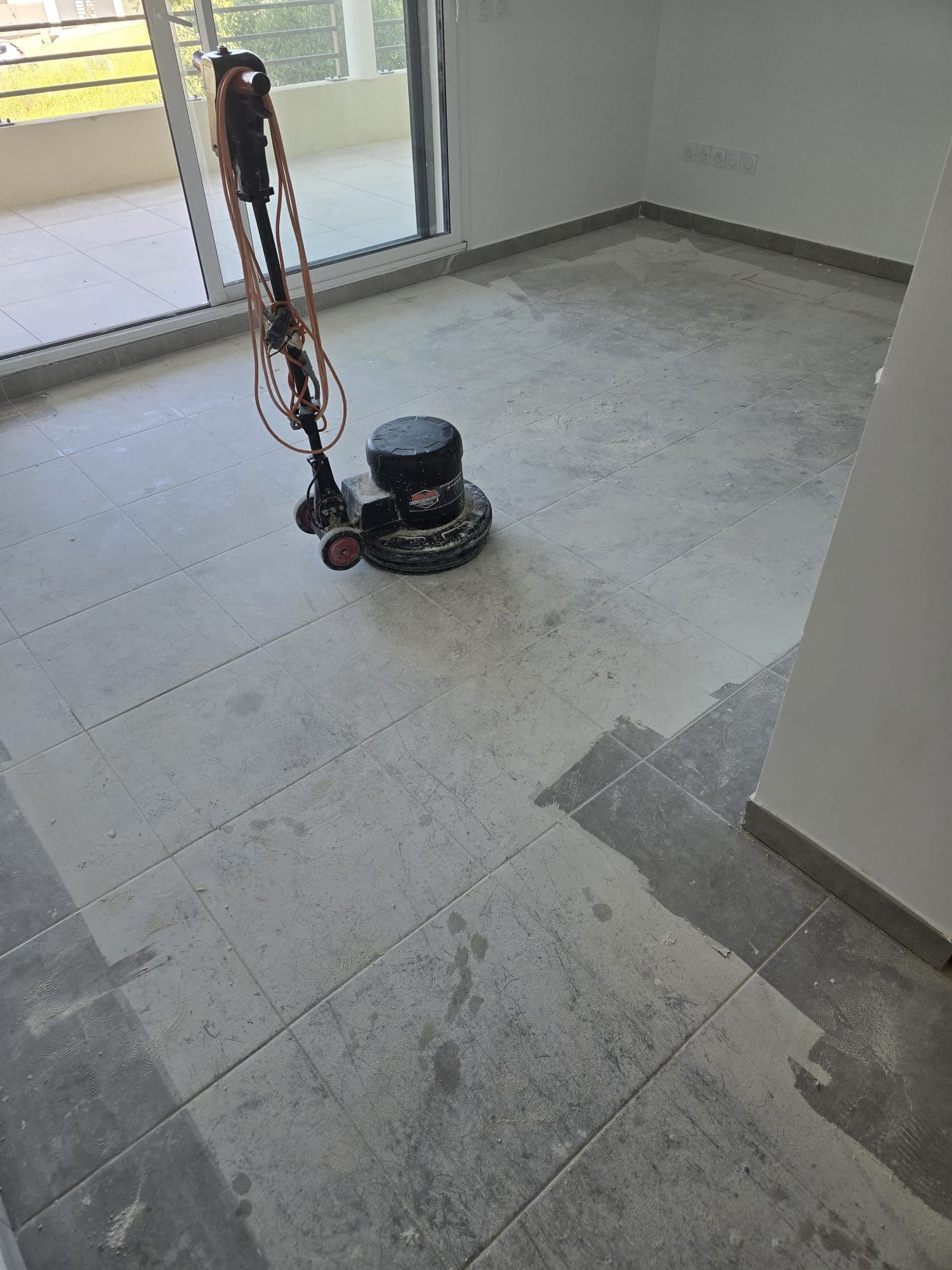Monobrosse en action sur un carrelage encore couvert de laitance de ciment