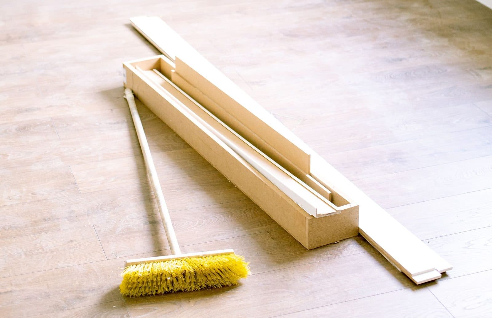Balai de chantier et plinthes en attente de pose sur un sol neuf